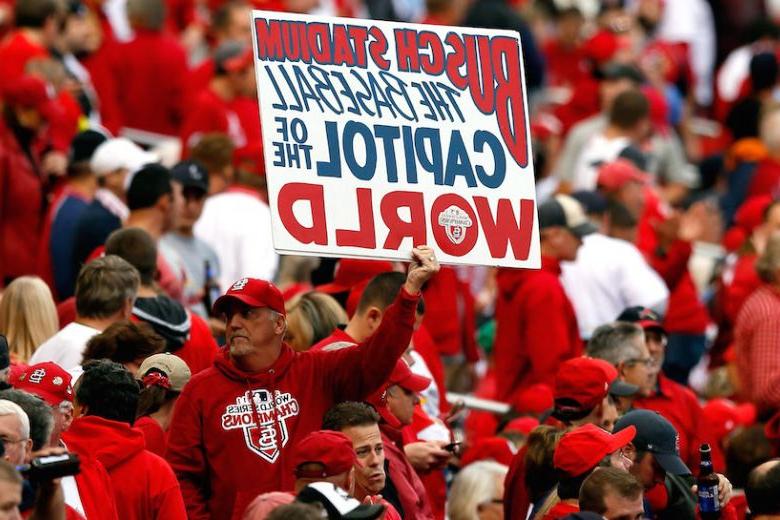 A St. 路易斯红雀队的一名球迷举着一块牌子，上面写着:“布希体育场:世界棒球之都。."